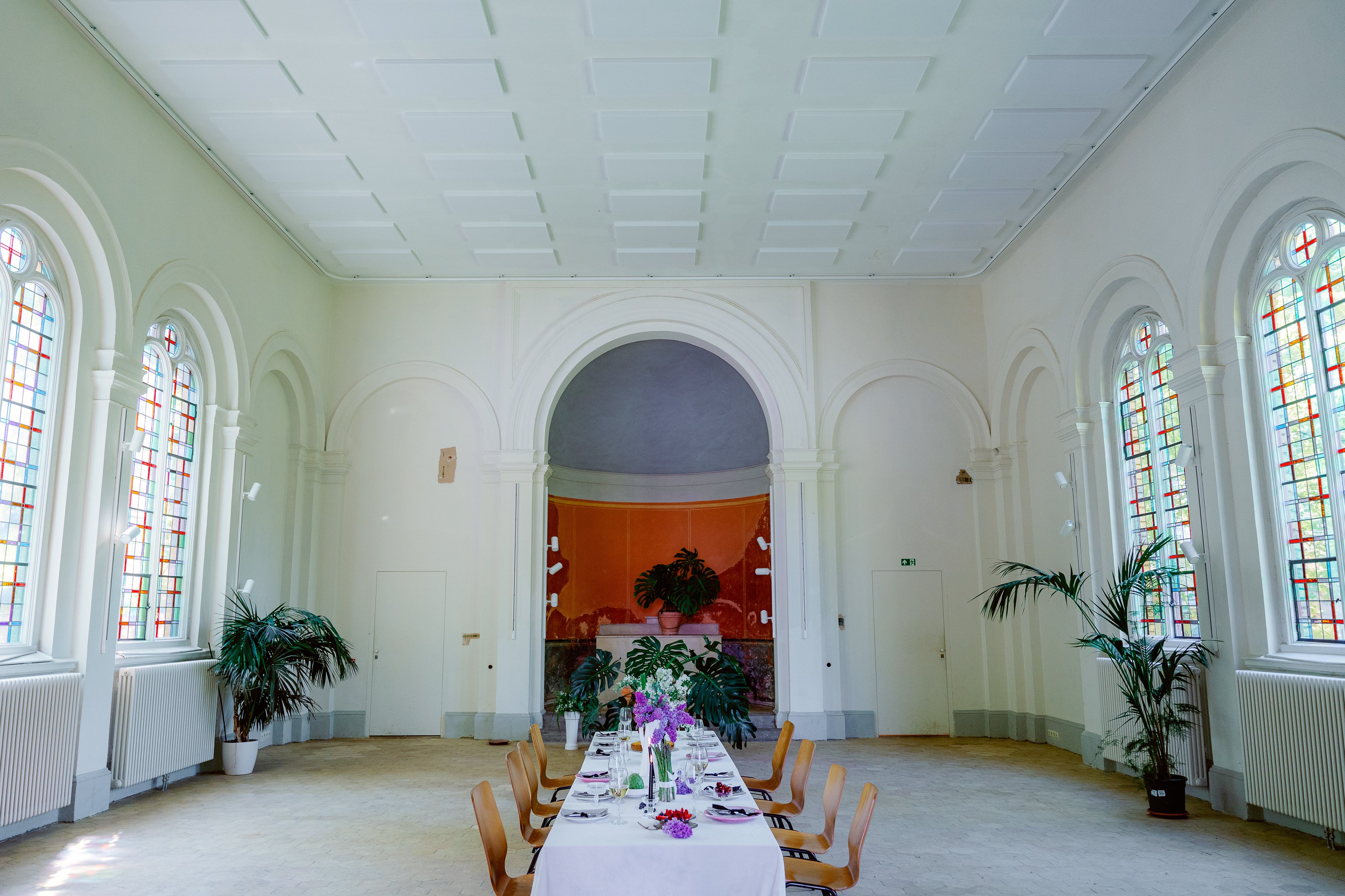 Ein Foto des inneren einer Kirche. In der Mitte steht eine lange Tafel mit Holzstühlen an den Seiten.
