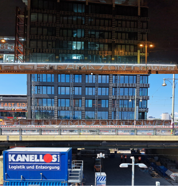 Ein Foto des Amazone Towers. Man sieht nur den unteren Teil des Towers, davor ist eine Baustelle. Auf dem Durchgang für Passanten durch die Baustelle steht "Fight Amazontower". Das gleiche Foto ist darüber geschnitten, diesmal ist es Nacht.