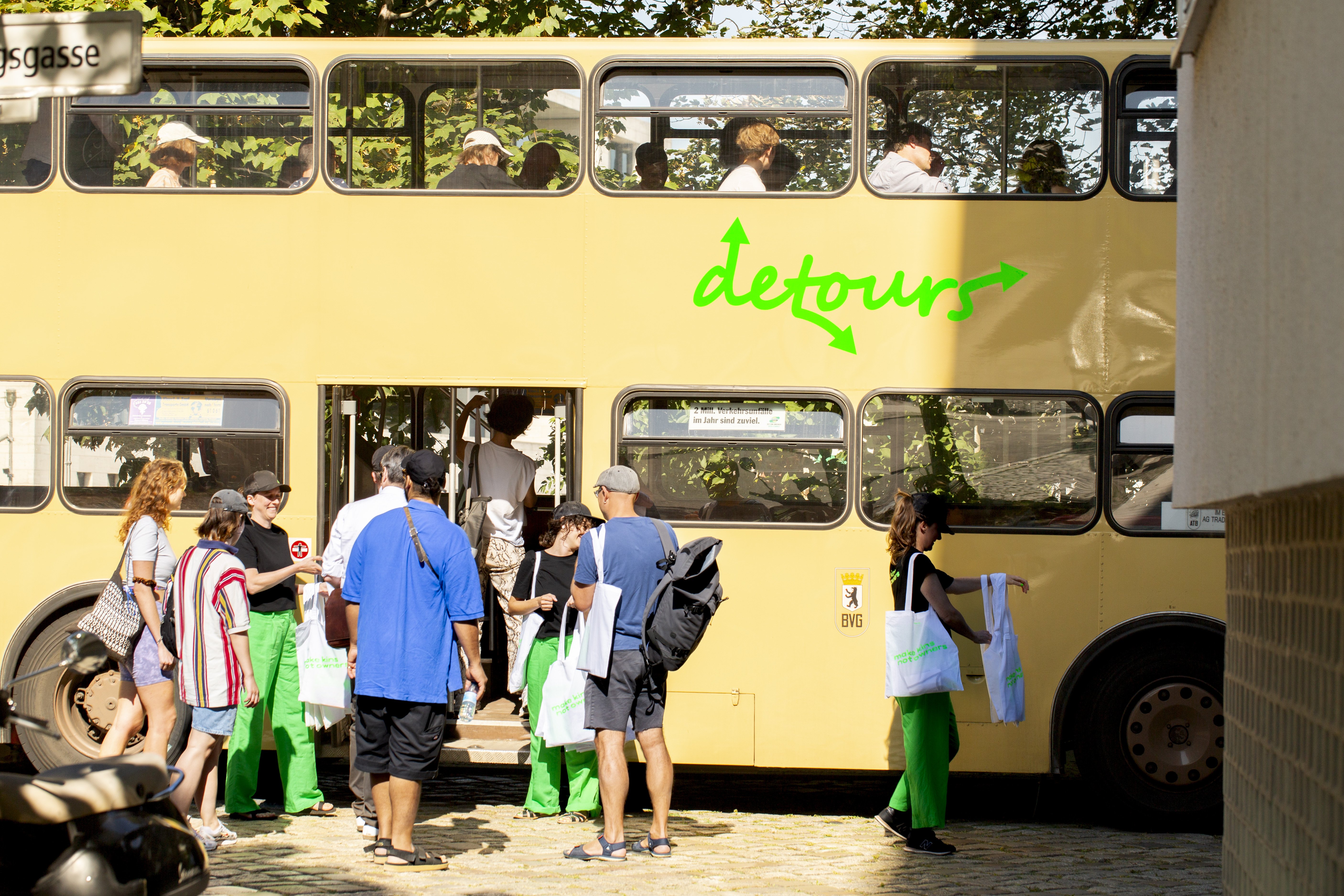 Menschen steigen in einen Doppeldecker Bus ein, auf dem detours steht.