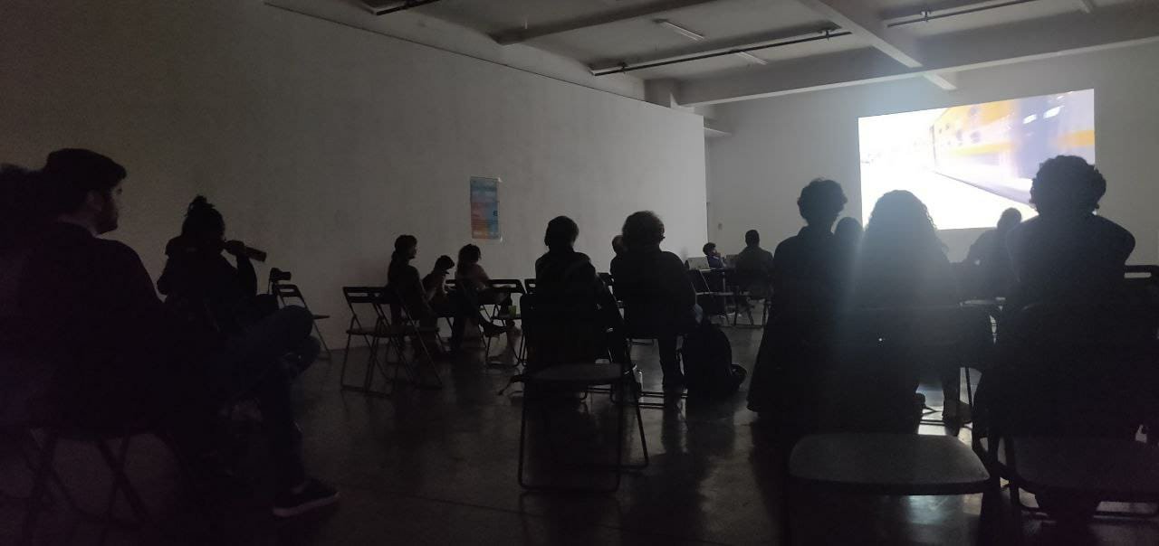 Etwa 15 Personen sitzen verteilt in einem abgedunkelten großen Raum und schauen nach vorne auf eine Wand, auf der ein Film projiziert wird. Der Film ist Teil der Egypt Cinema Filmreihe.