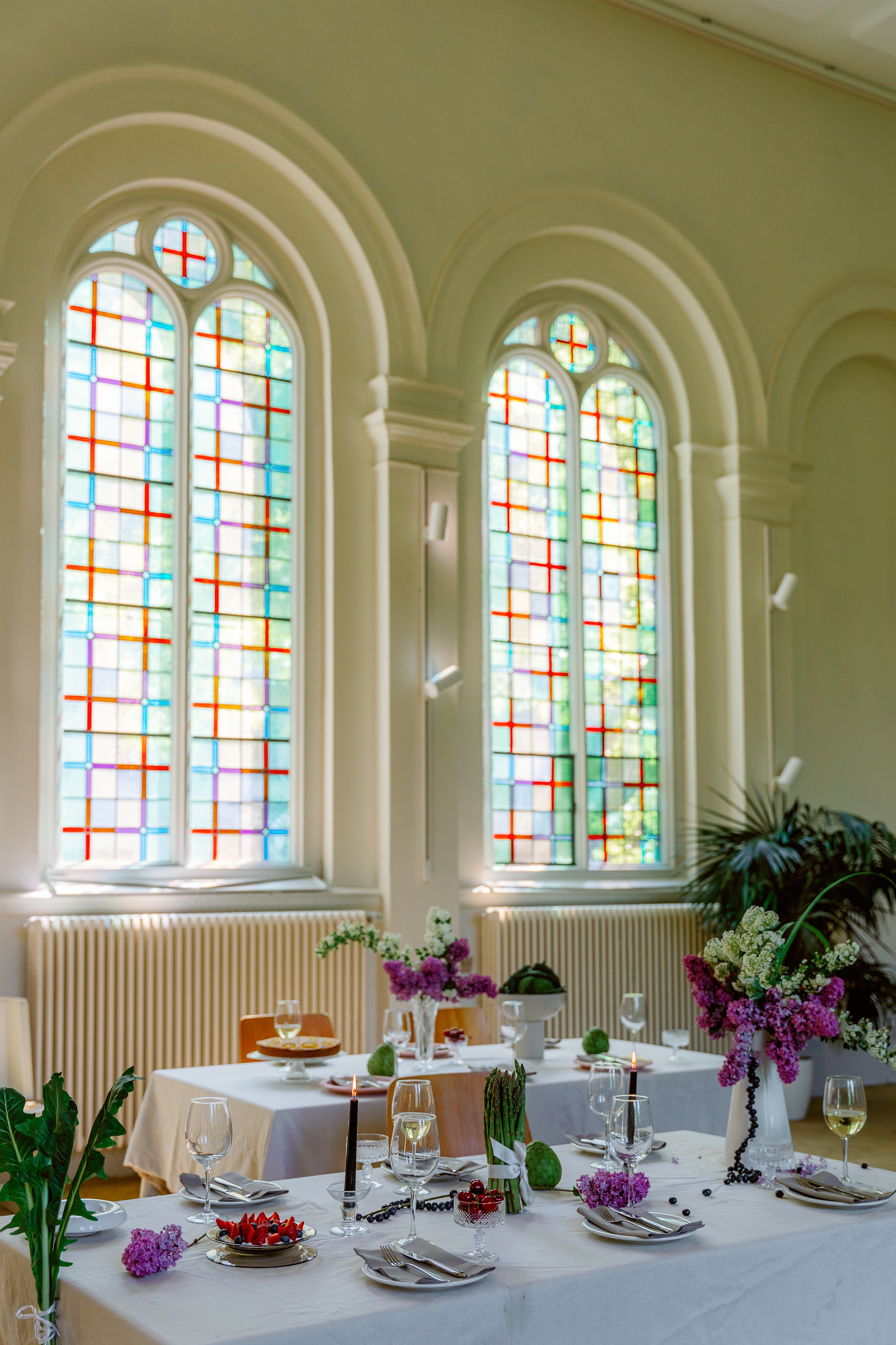 Ein Foto einer Kirche mit bunten Fenstern. In der Kirche steht eine gedeckte Tafel.
